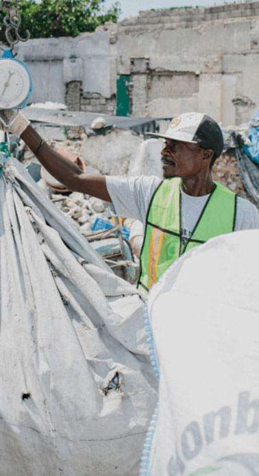 Afbeelding van een man die een stapel plastic afval voor eenmalig gebruik op straat opruimt en weegt