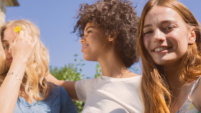 Group of female friends with different hair types laughing in the sun